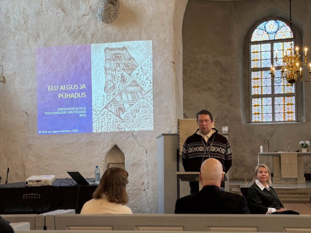 Ettekandja pulbi taga, ekraanil pealkiri „Elu algus ja pühadus“