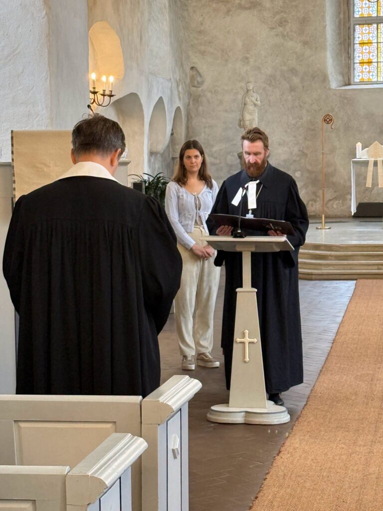 Lugeja kantslipuldi ääres, ees vaimulik